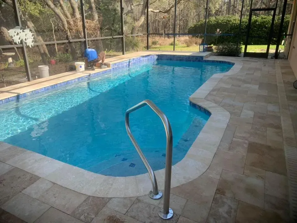 Swimming pool with blue tile, light tile decking, and a metal handrail.