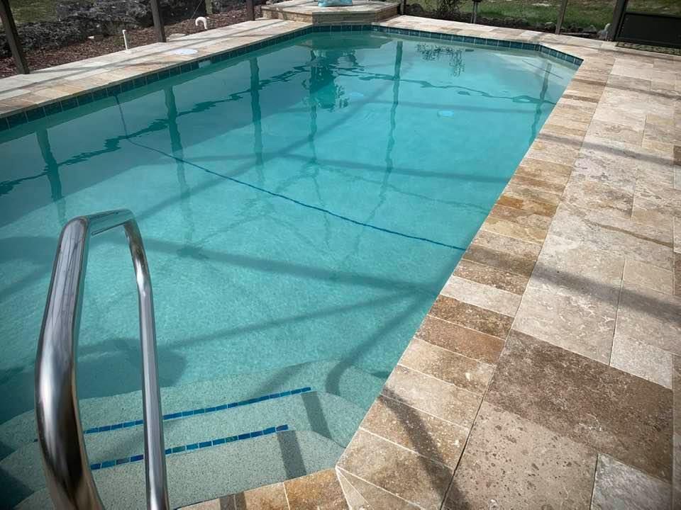 Swimming pool with turquoise water and stone deck. Stainless steel handrail, pool steps visible.