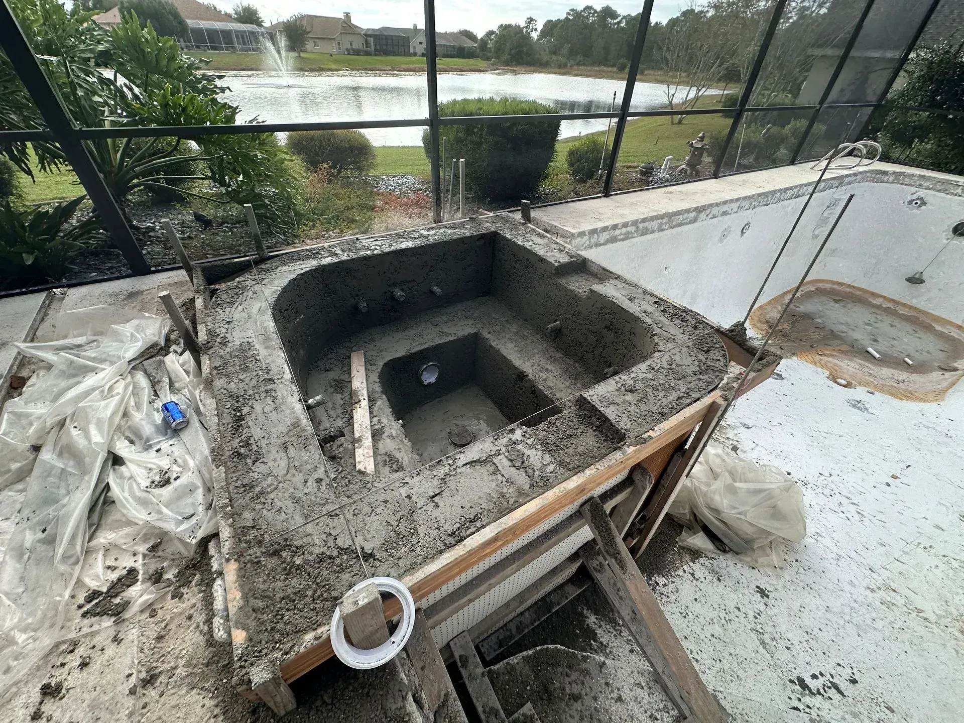 Pool spa under construction outdoors, framed with concrete, unfinished, overlooking a lake.
