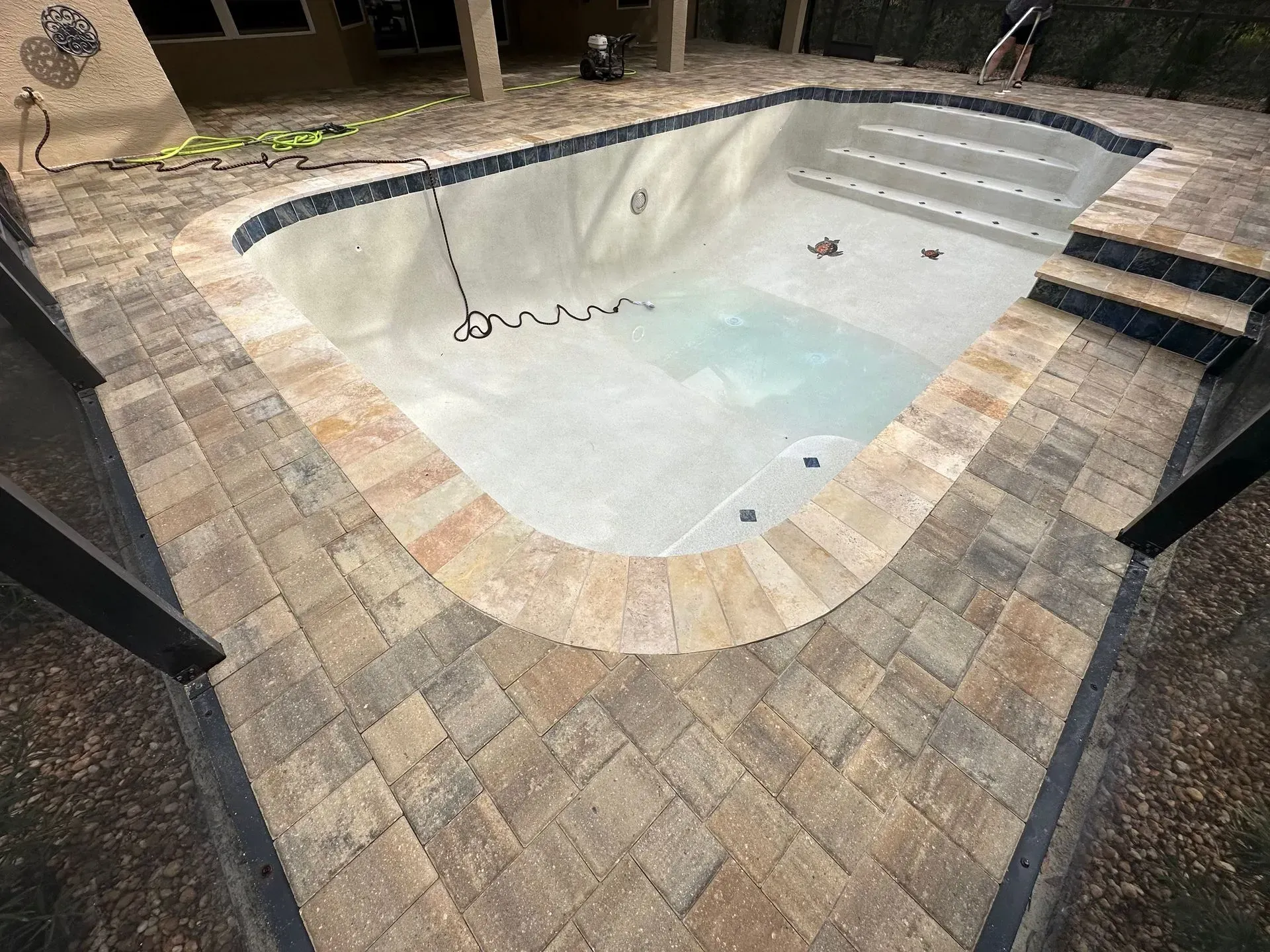 Pool with stone pavers surrounding it. Steps lead into the pool.