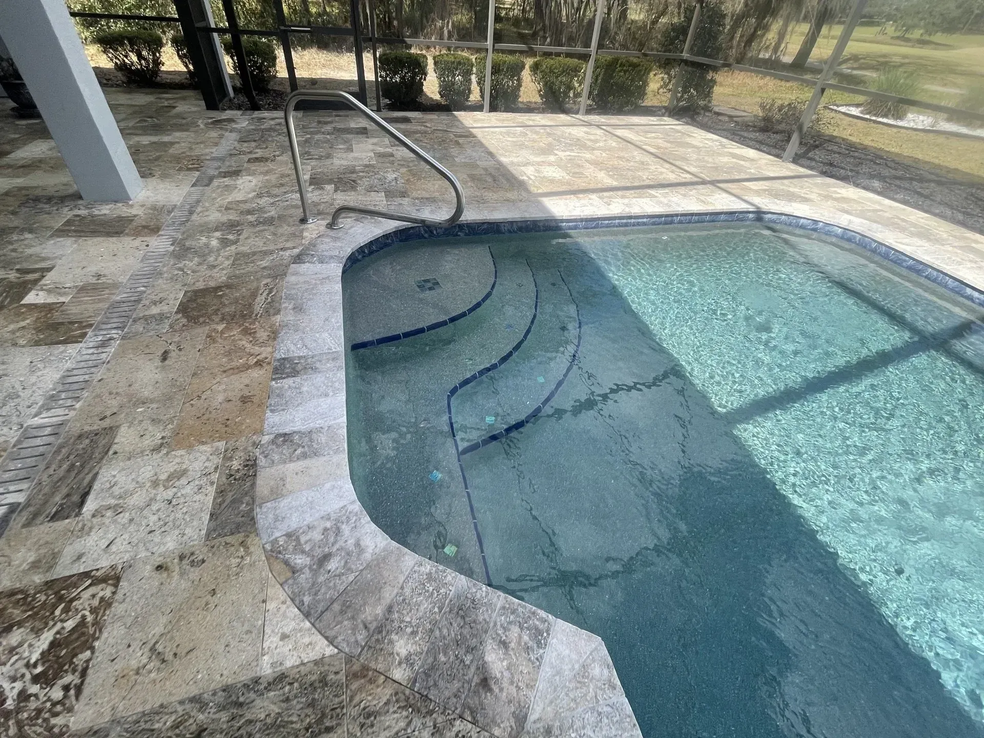Pool with steps and handrail; travertine patio.