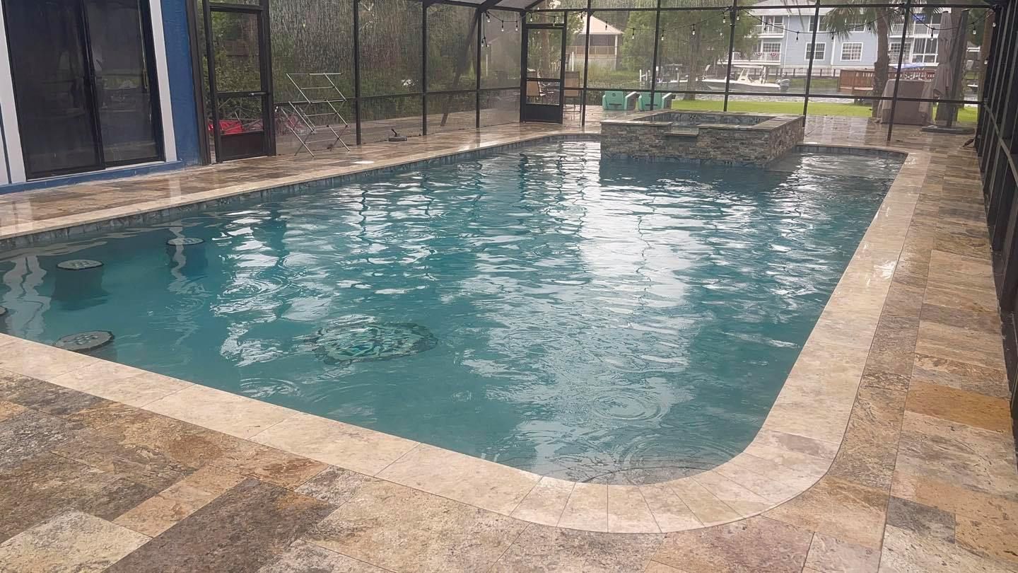 A rectangular pool with light brown tile surrounding it, and a rock feature in the center. Enclosed in a black screen.