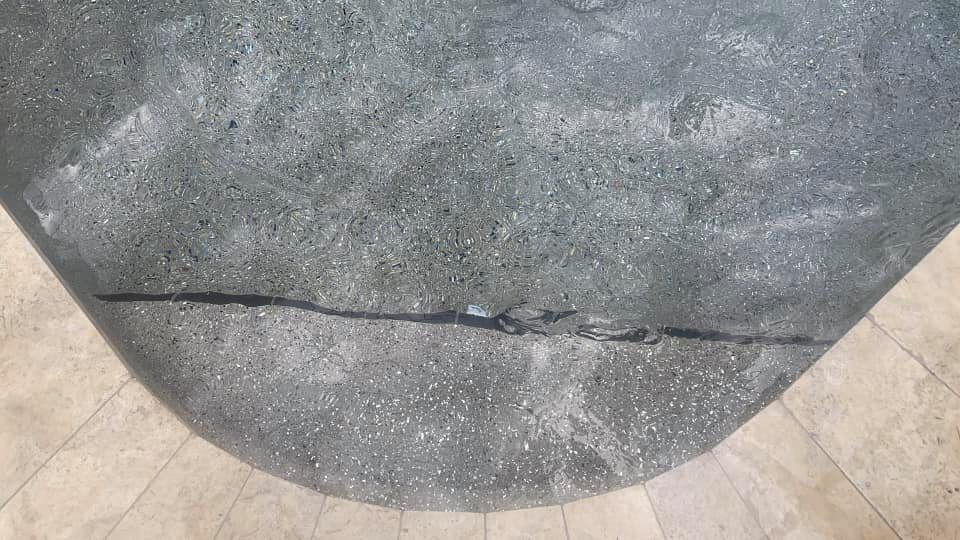 Gray concrete with a black crack across its curved surface, contrasting with a light beige border.