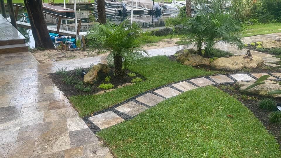 Landscaped yard with grass path, palm trees, and waterfront dock.