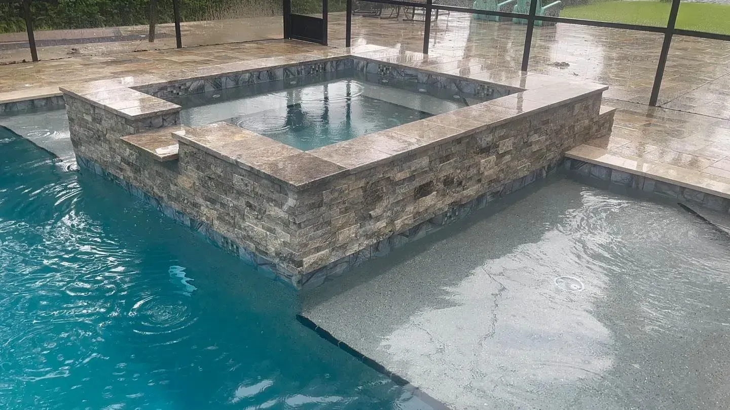 Outdoor pool with a built-in spa; blue water and stone surround.