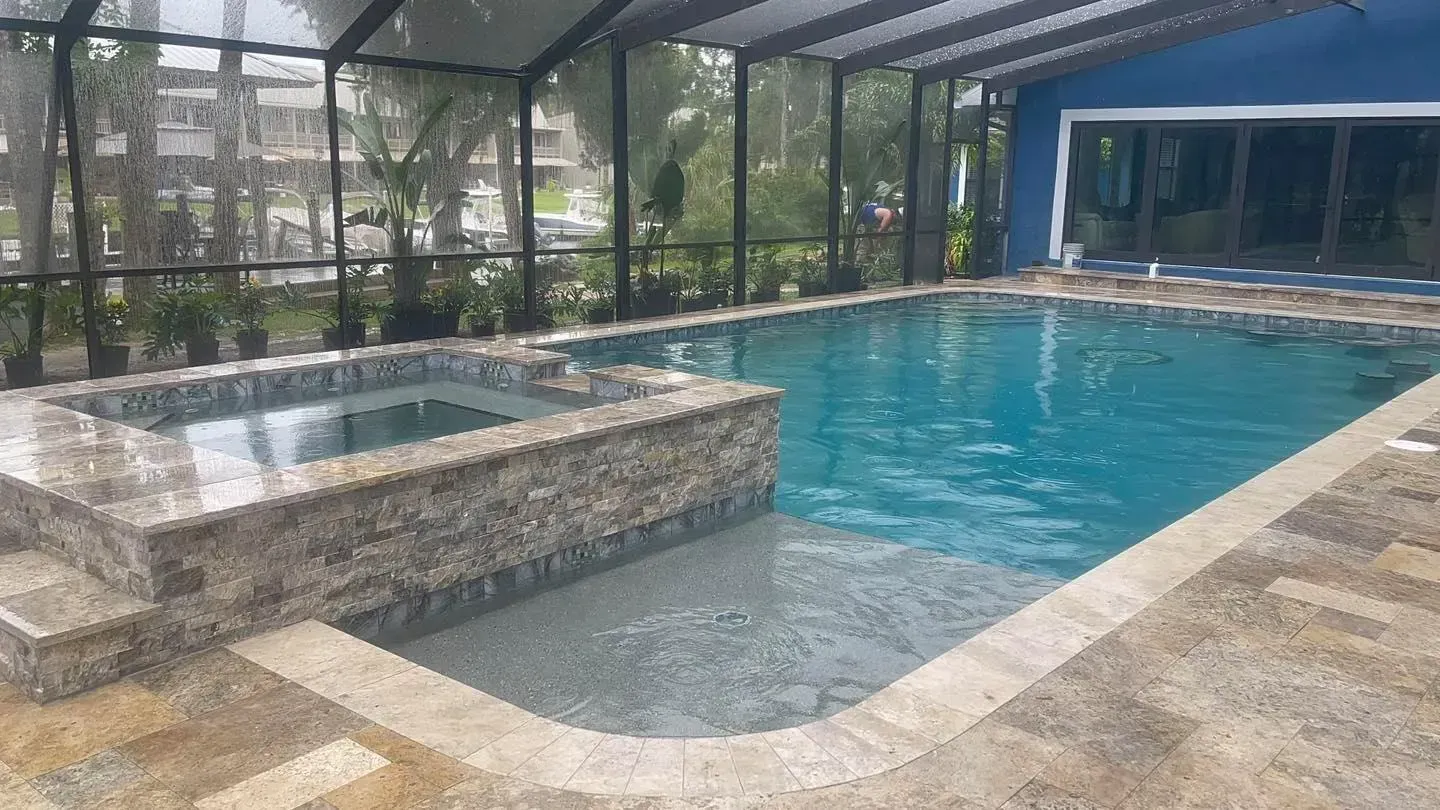 Swimming pool with attached spa, screened enclosure, and blue house.