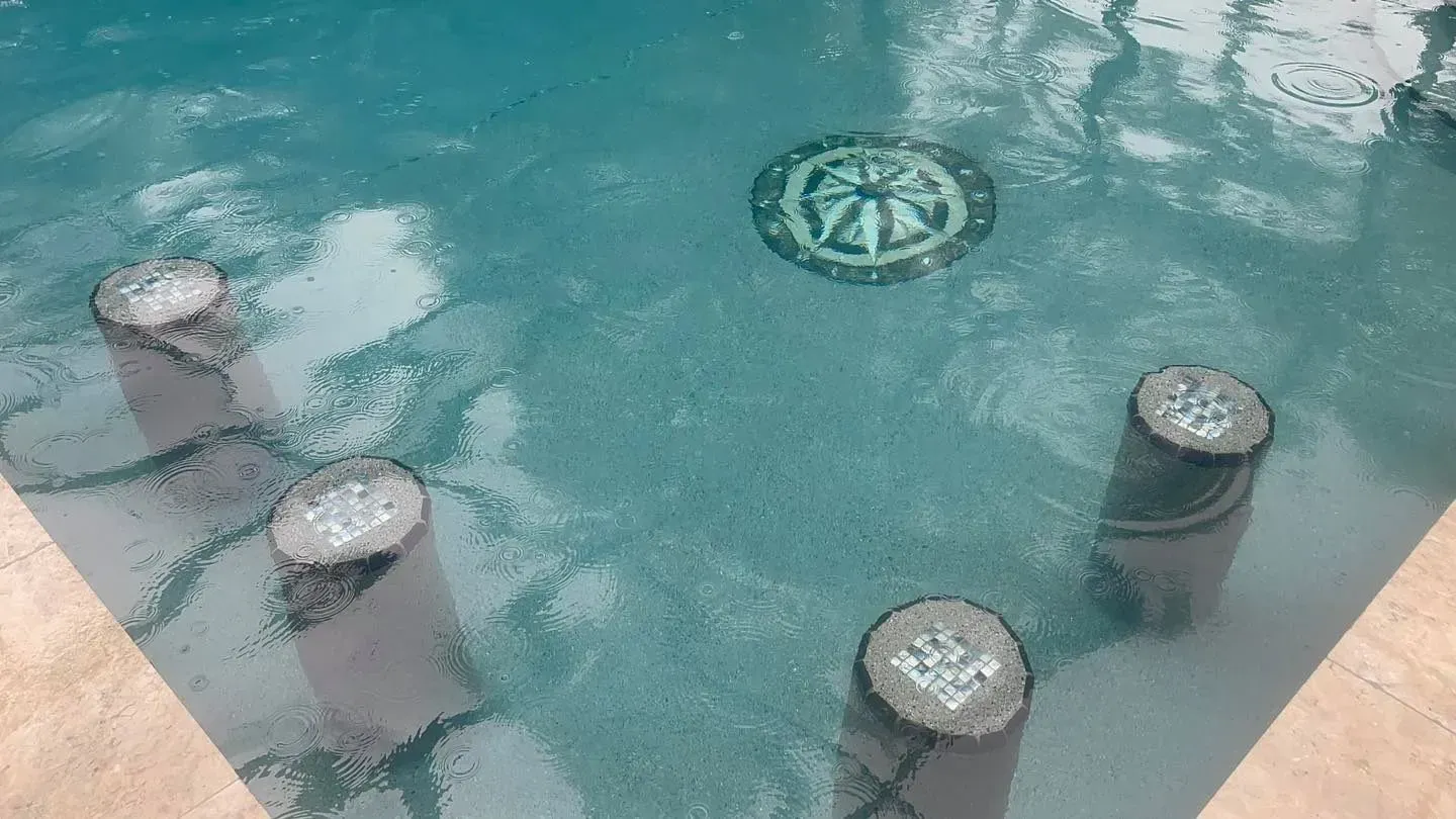 Pool with underwater columns and a mosaic design on the floor. Clear, turquoise water.