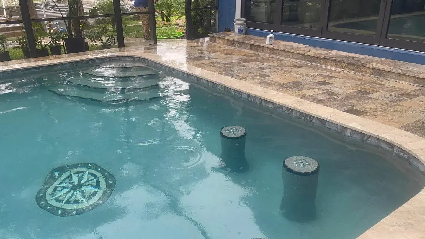 Swimming pool with built-in seats and steps, a mosaic design, and wet surrounding deck.