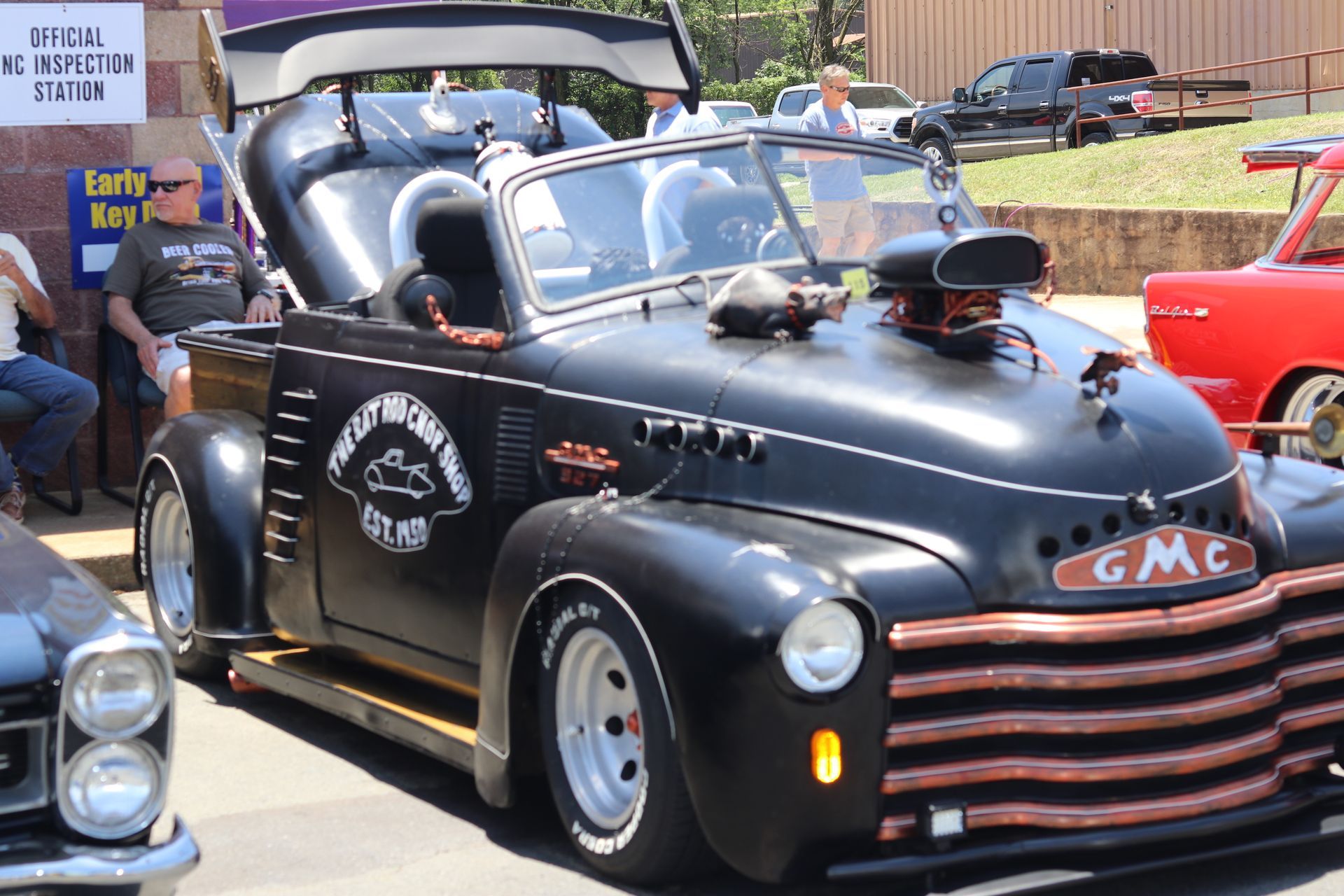 Black vintage GMC hot rod convertible at a car show, with chrome engine and custom paint