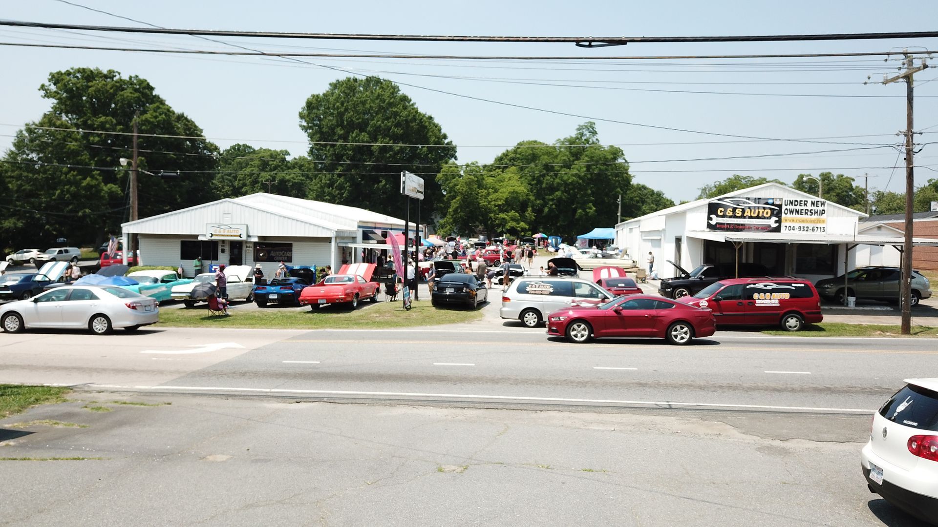 Car lot with many parked cars in front of a small building on a sunny day
