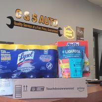 Cleaning supplies on a counter in a shop, including Lysol wipes, Hefty trash bags, and an Amazon box.