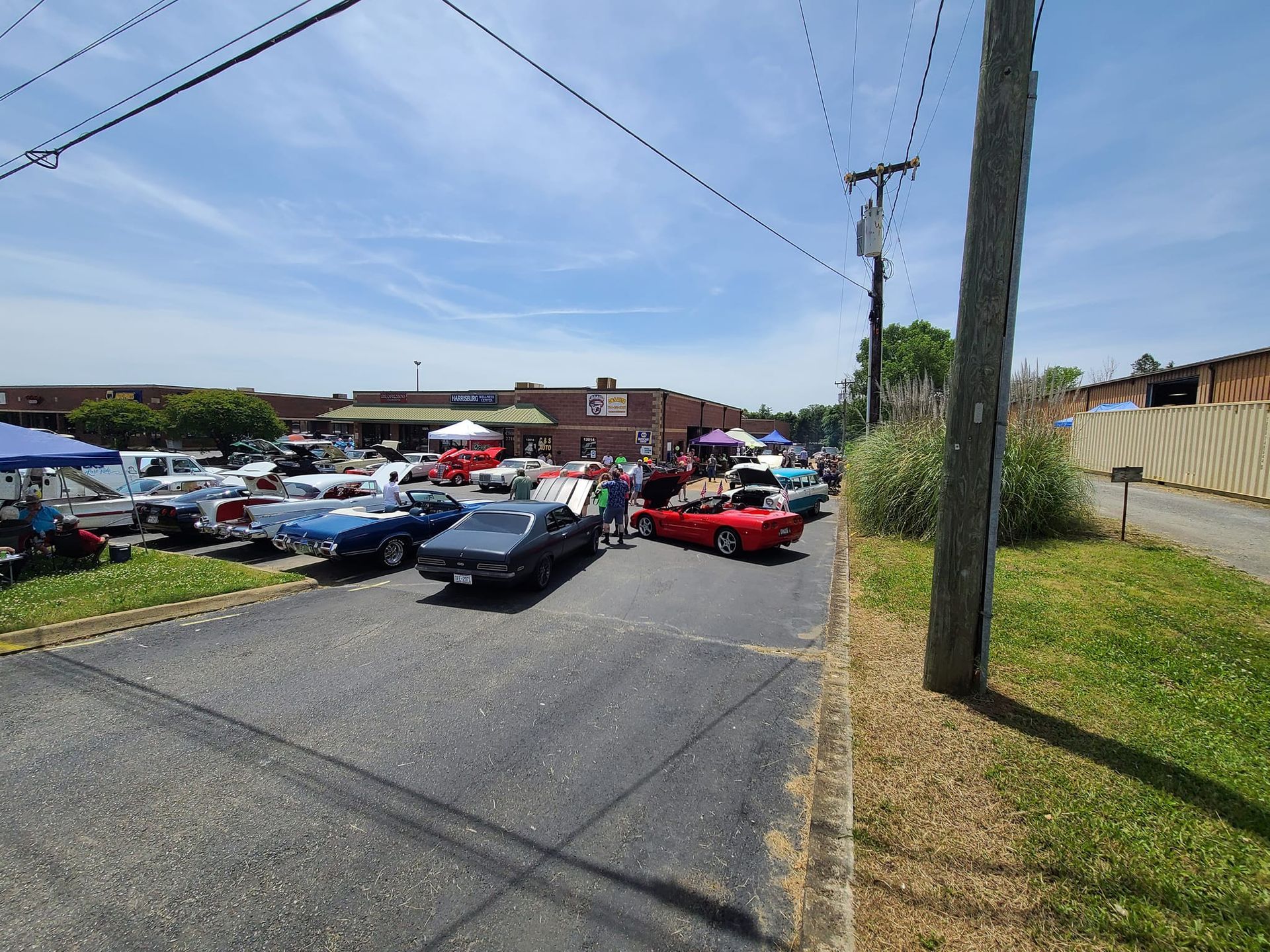 Classic cars lined up in a parking lot at an outdoor car show on a sunny day