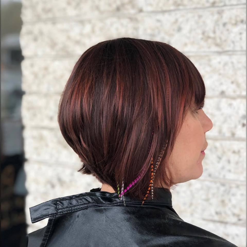 A woman with short brown hair is wearing a black cape