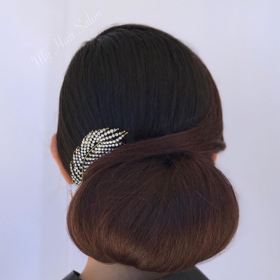 A woman has her hair in a bun with a brooch in it