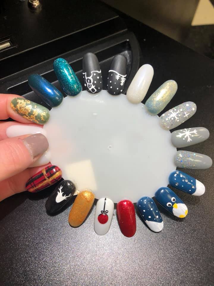 A person is holding a display of nails with different designs on them