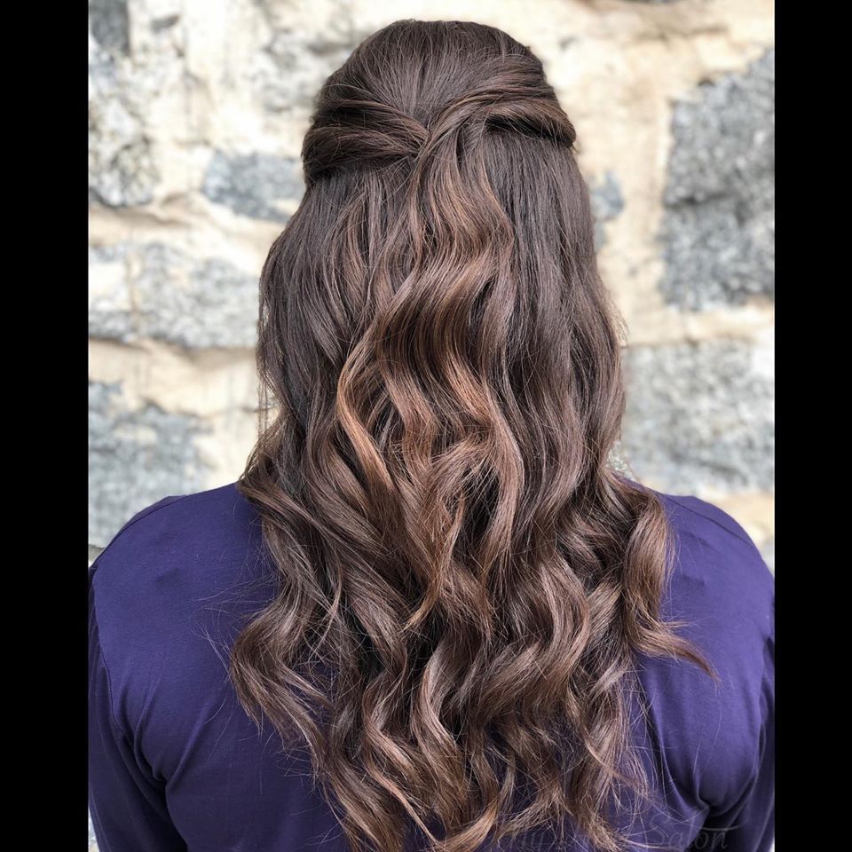 A woman with long brown hair is wearing a half up half down hairstyle.