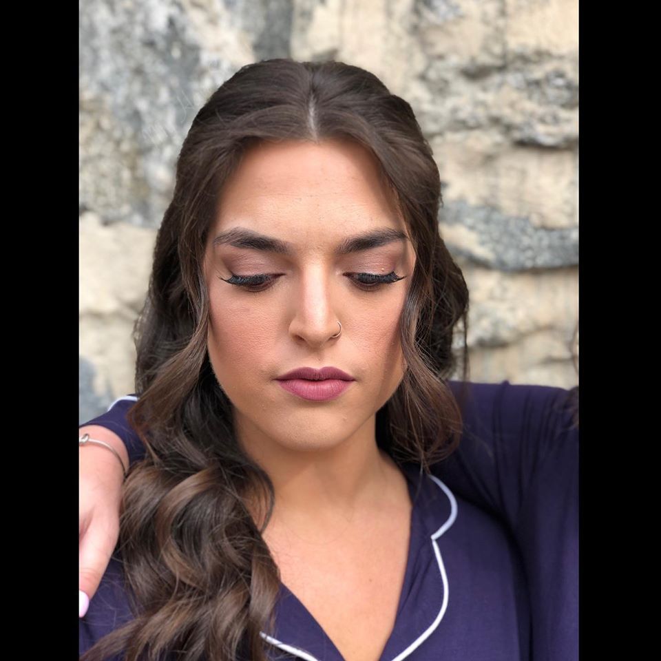 A close up of a woman 's face wearing a purple shirt.