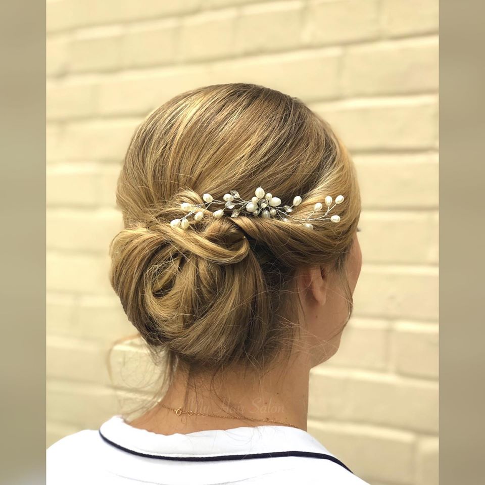 A woman is wearing a bun with pearls in her hair.