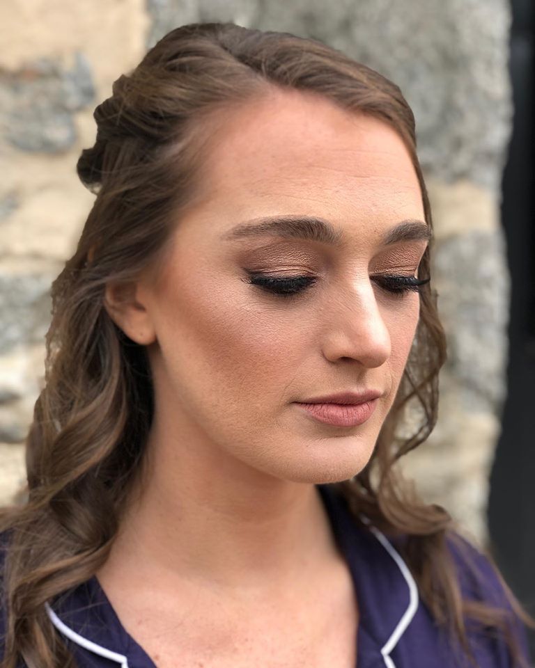 A close up of a woman 's face wearing a purple shirt.