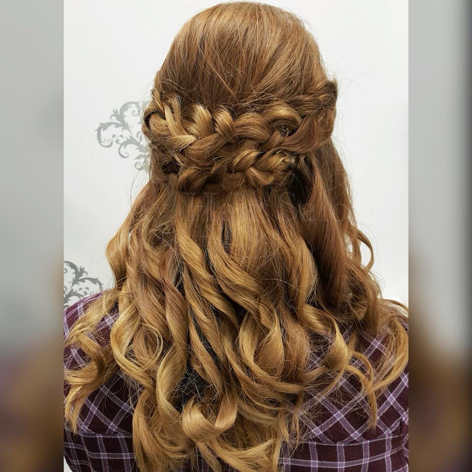 A woman with long hair is wearing a plaid shirt and has her hair in a half up half down braid.