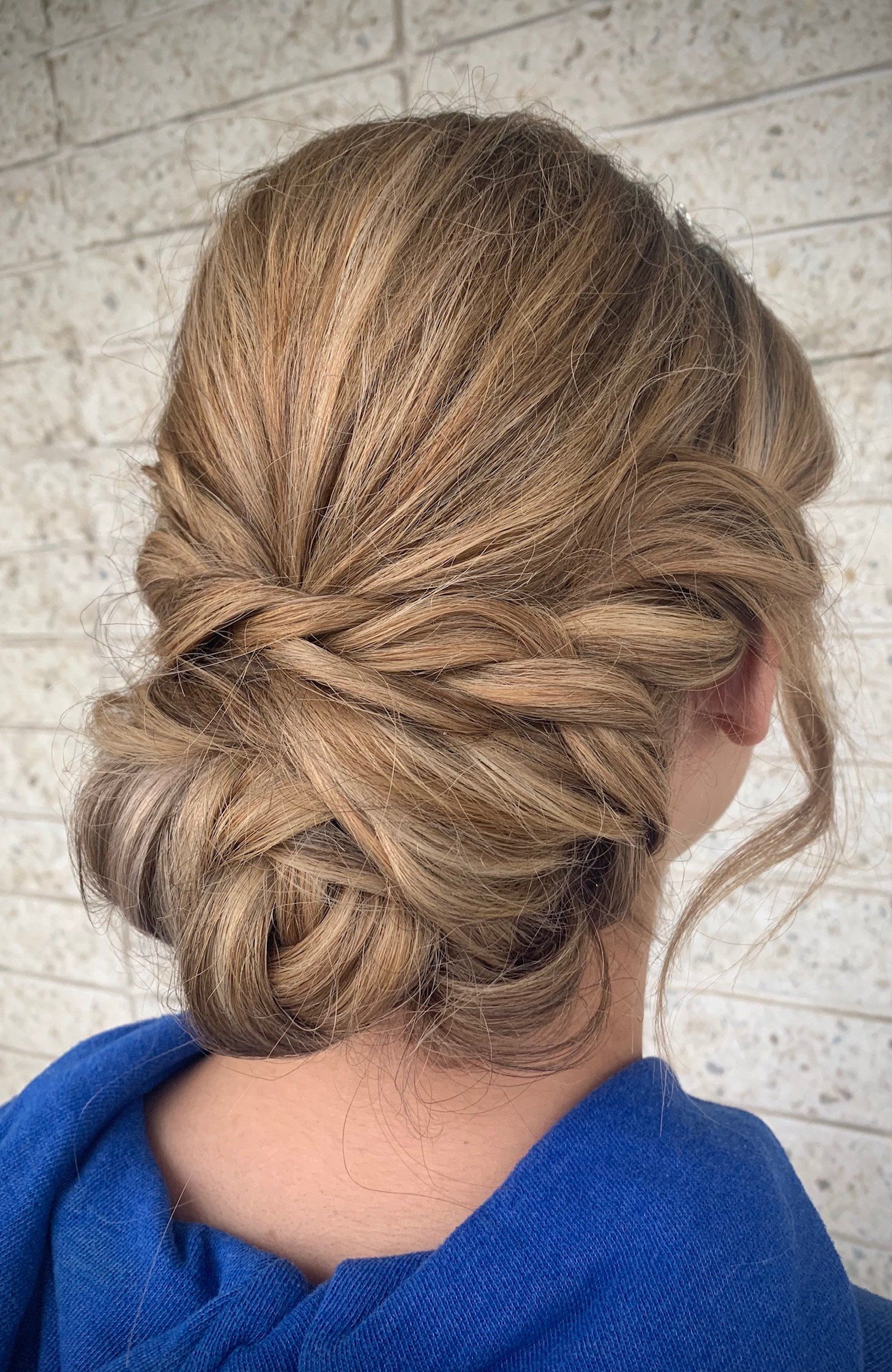 A woman is wearing a blue sweater and has her hair in a bun.