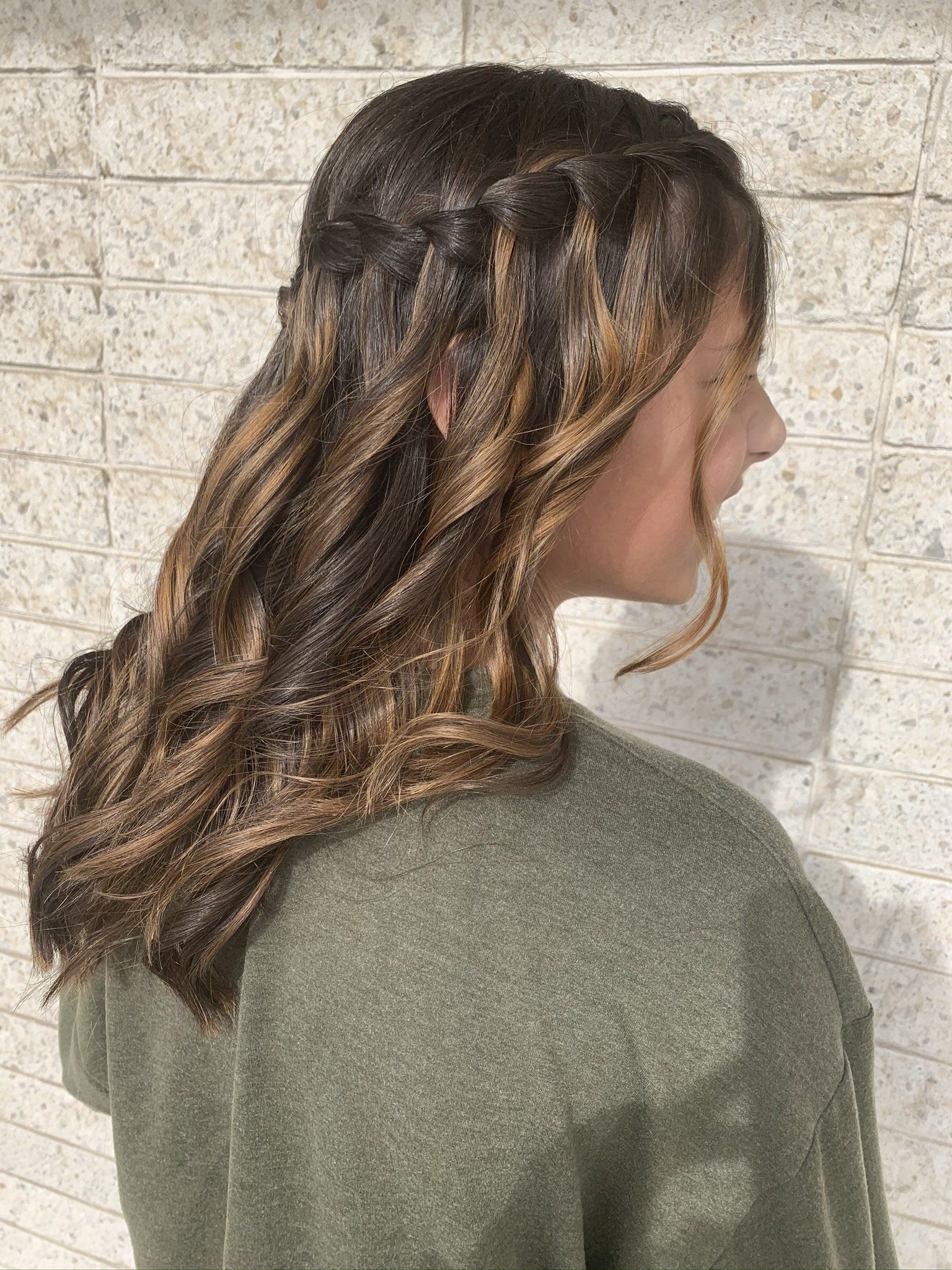 The woman is wearing a green sweater and has a braid in her hair.