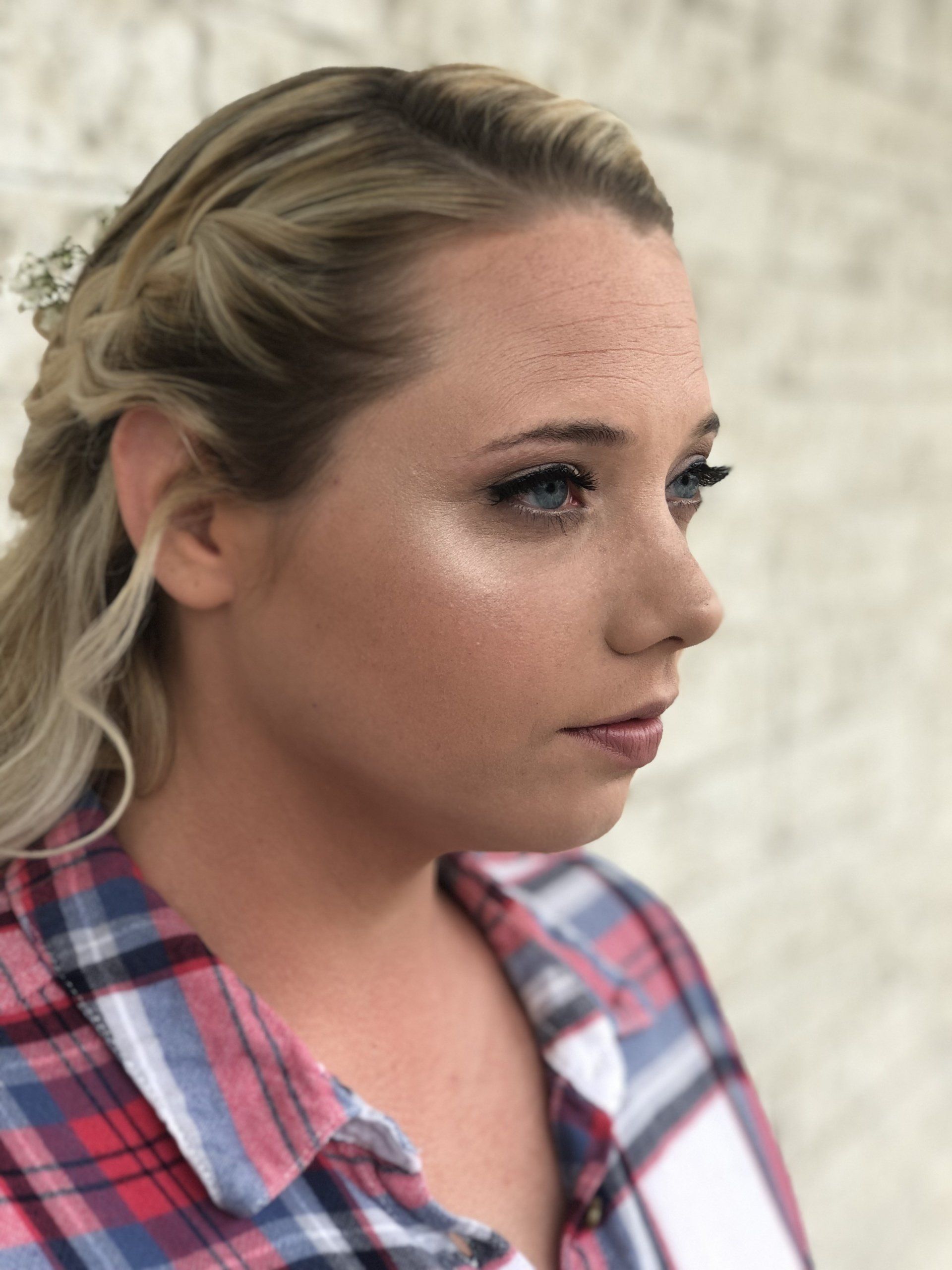 The woman is wearing a plaid shirt and has freckles on her face.