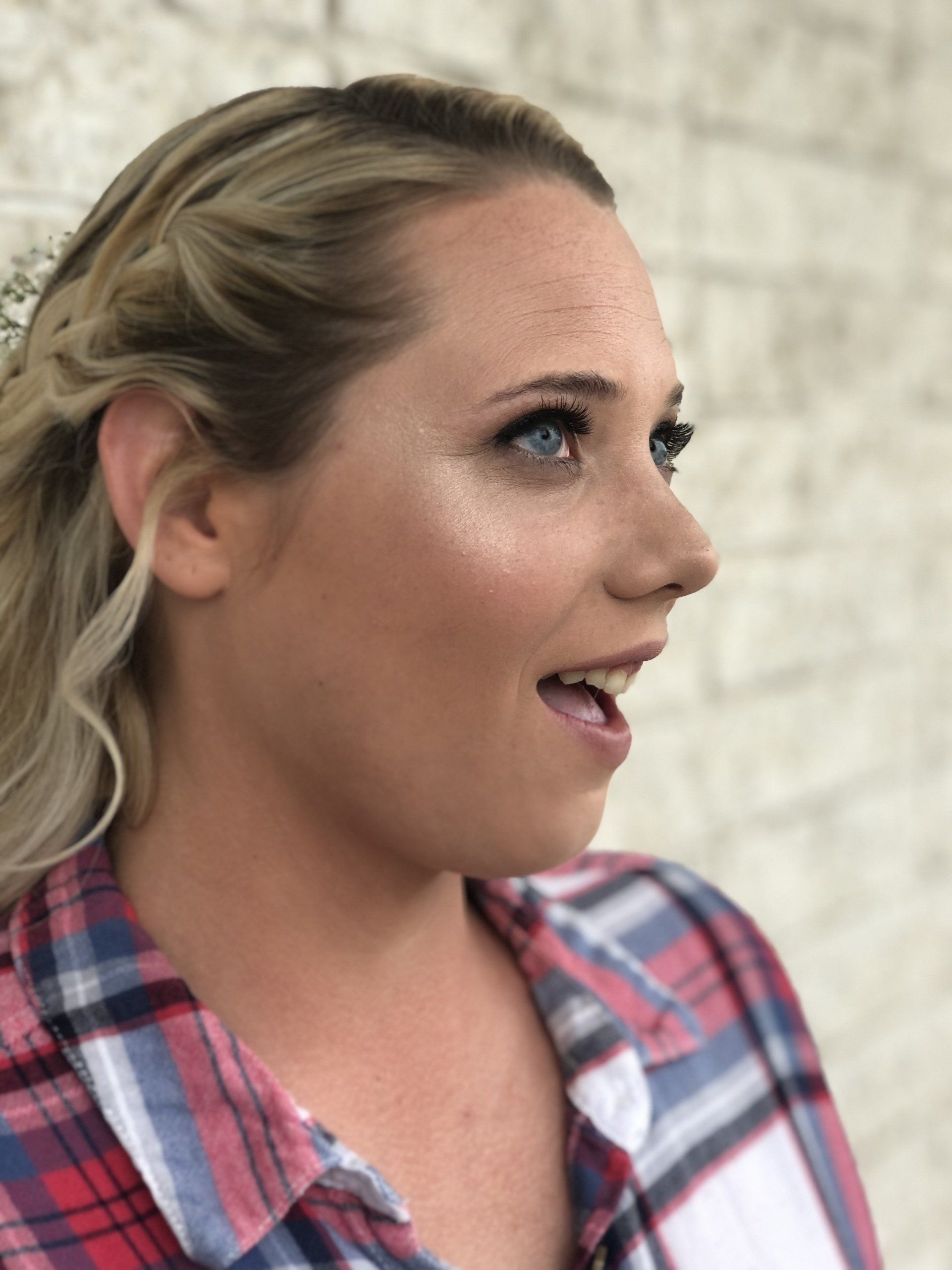 The woman is wearing a plaid shirt and has her mouth open.