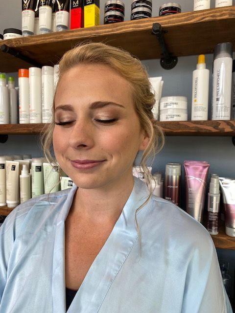 A woman in a blue robe is standing in front of a shelf of hair products.