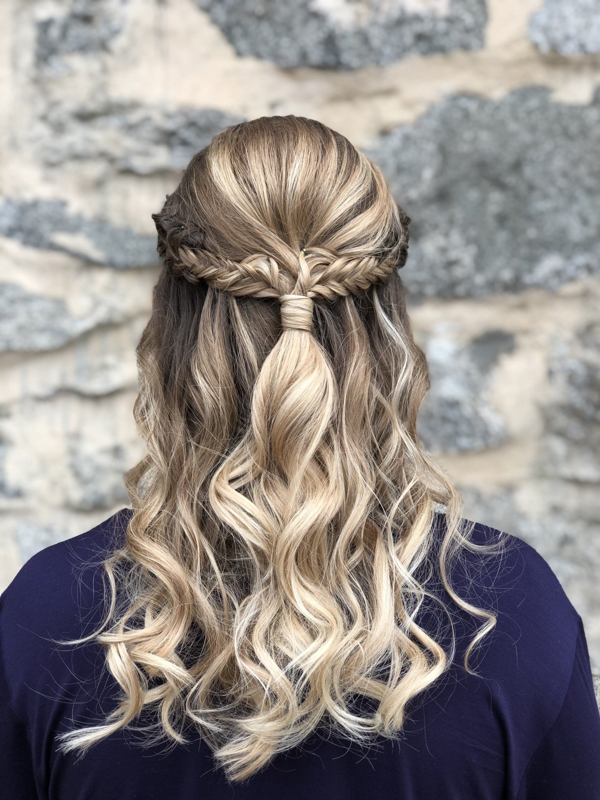 A woman with long blonde hair is wearing a half up half down hairstyle.