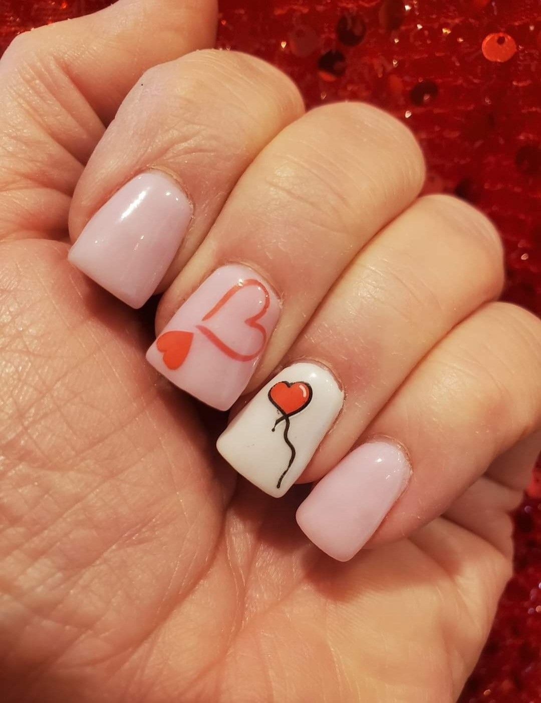 A close up of a woman 's nails with a heart and balloon design