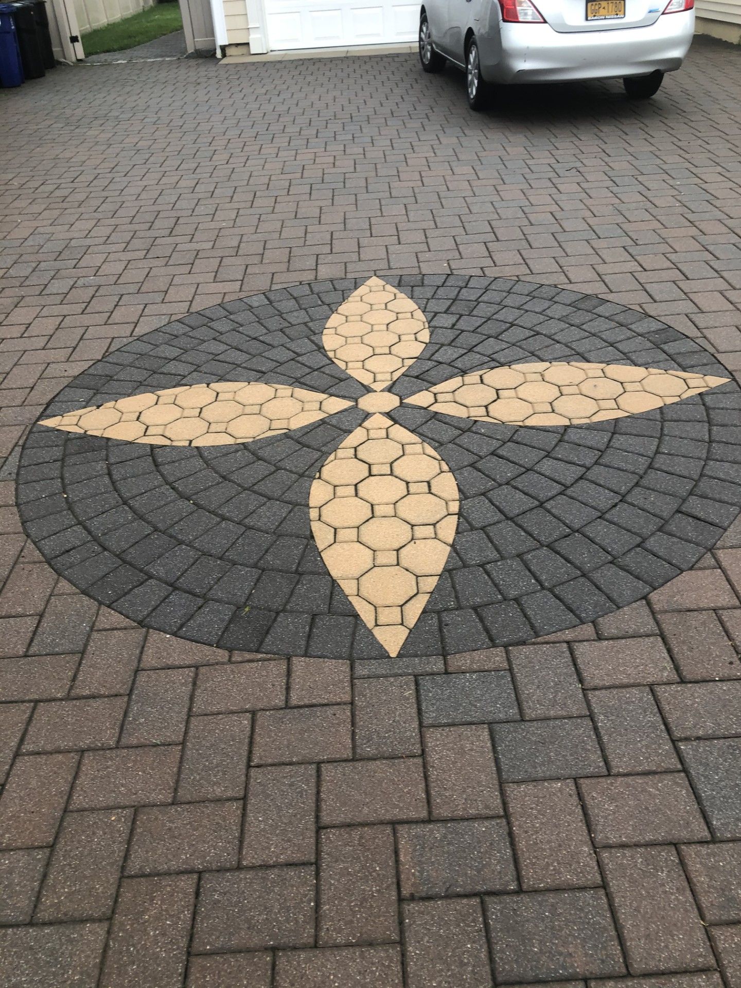 A car is parked in a driveway with a circular design on it.