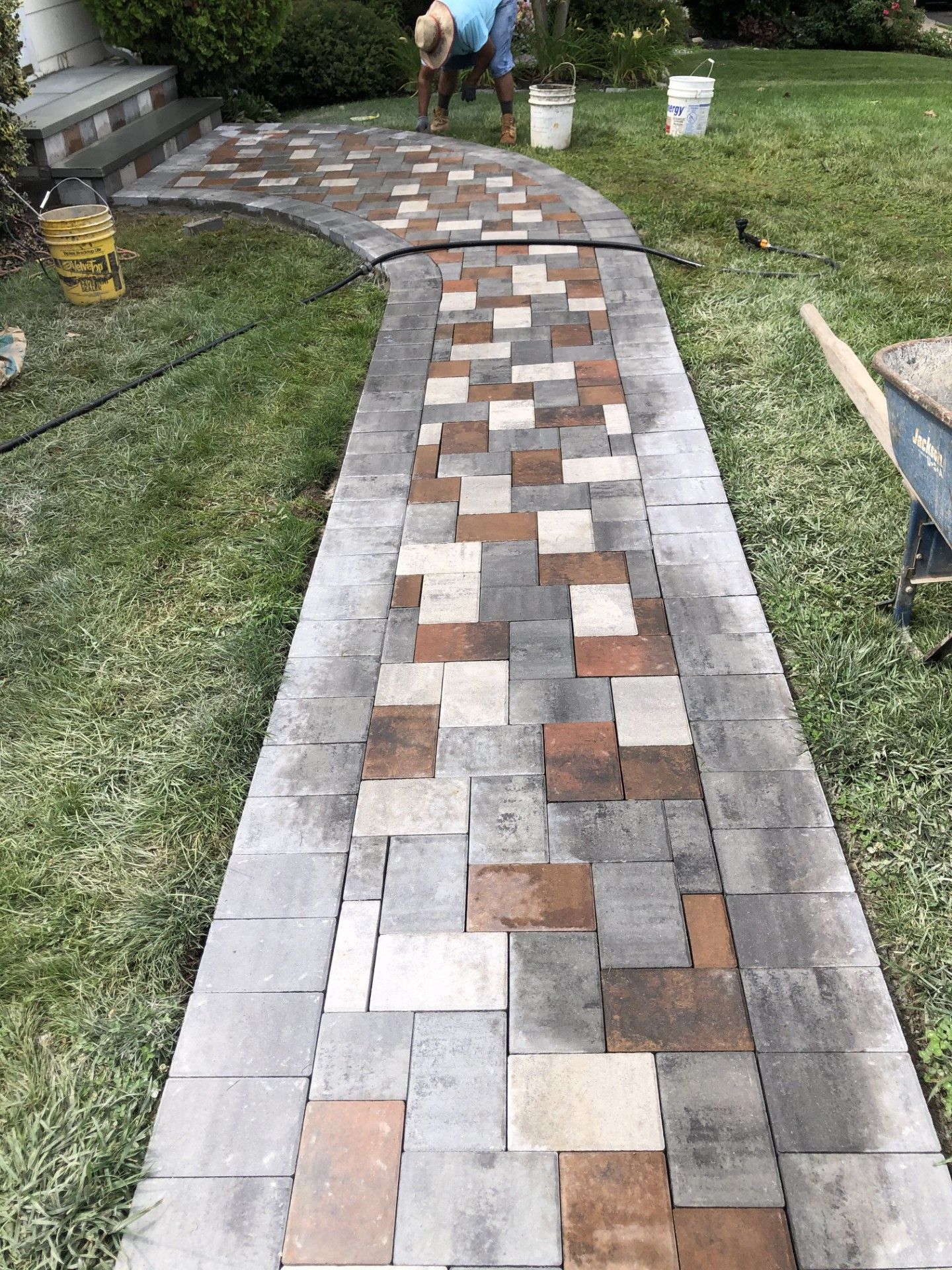 A brick walkway is being built in a backyard.
