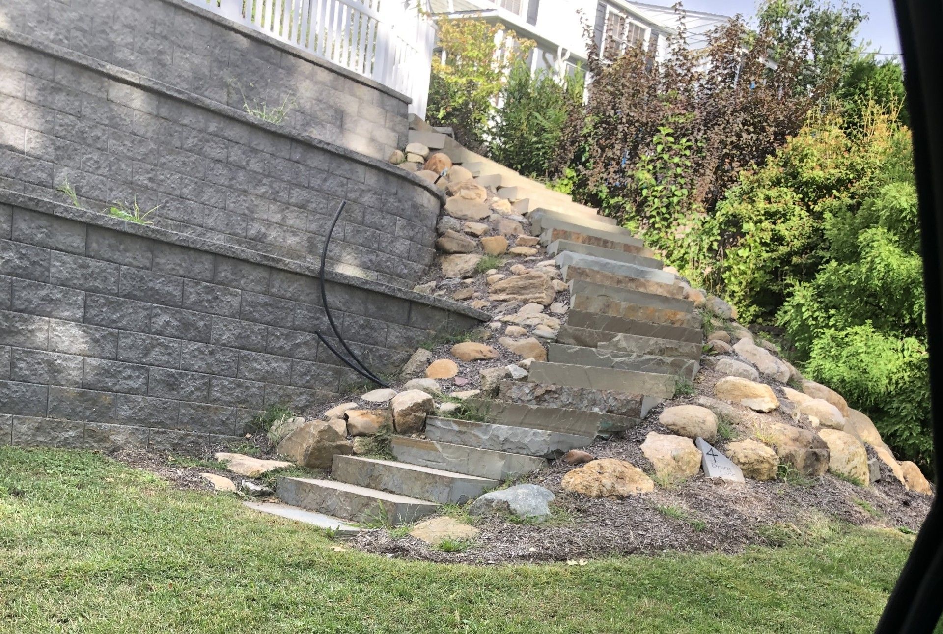 A stone wall with stairs leading up to it in a yard.