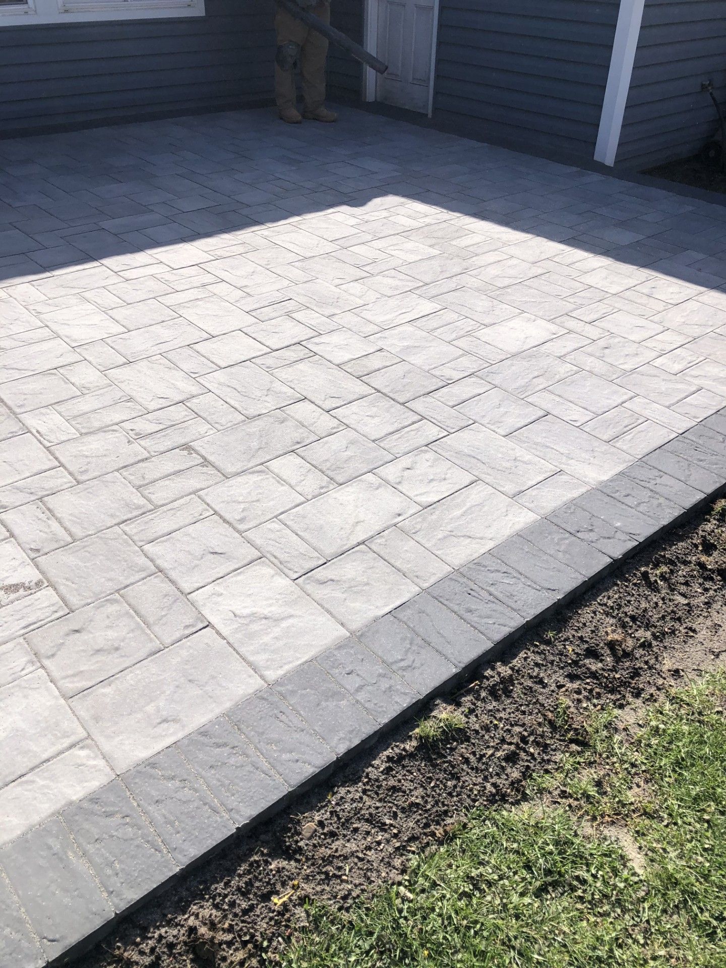 A brick driveway is being built in front of a house.