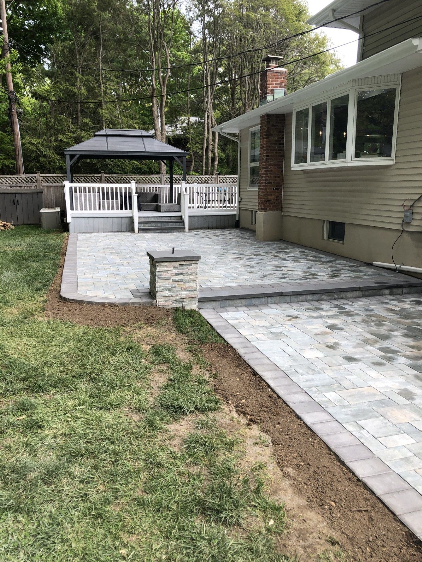 A patio with a gazebo in the backyard of a house.