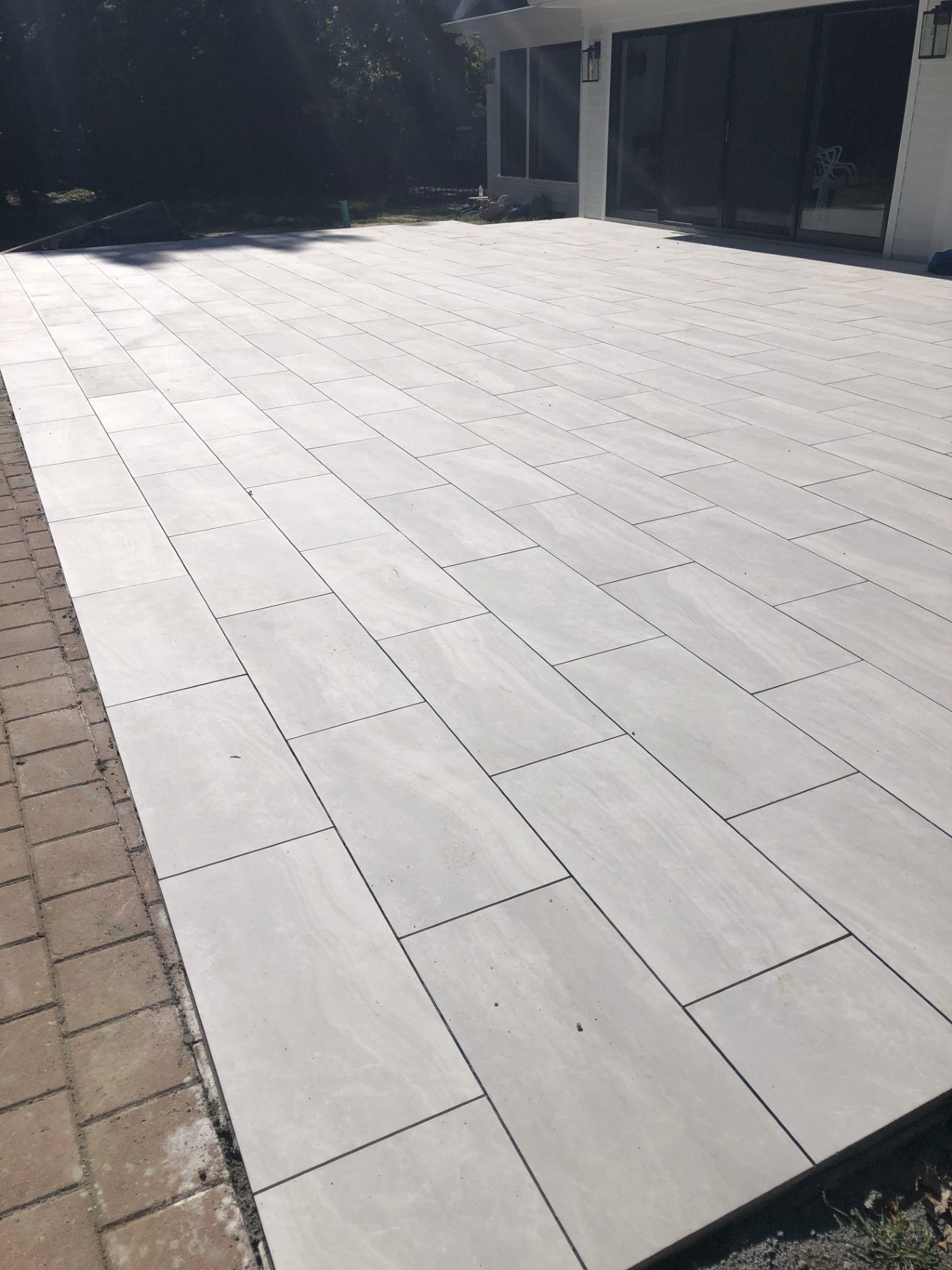 A large white tiled patio in front of a house.