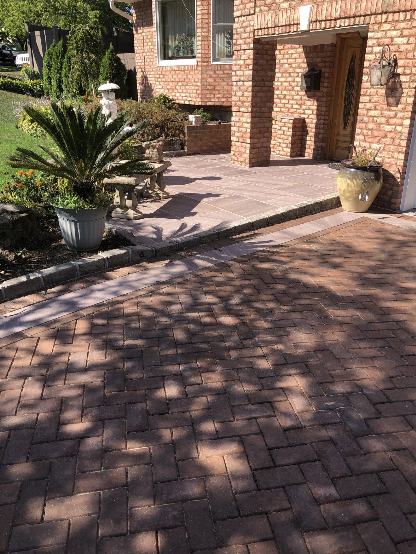 A brick driveway with a patio in front of a brick house.