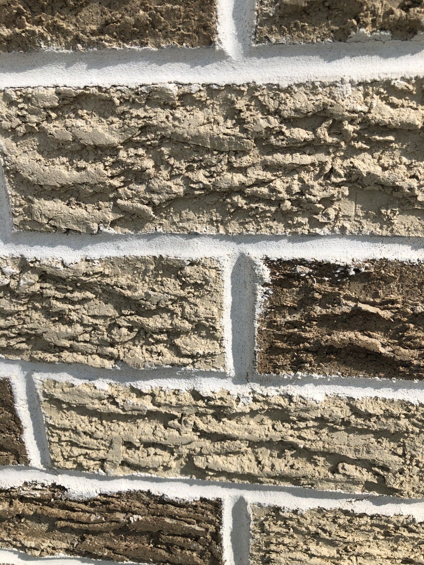 A close up of a brick wall with white paint on it.