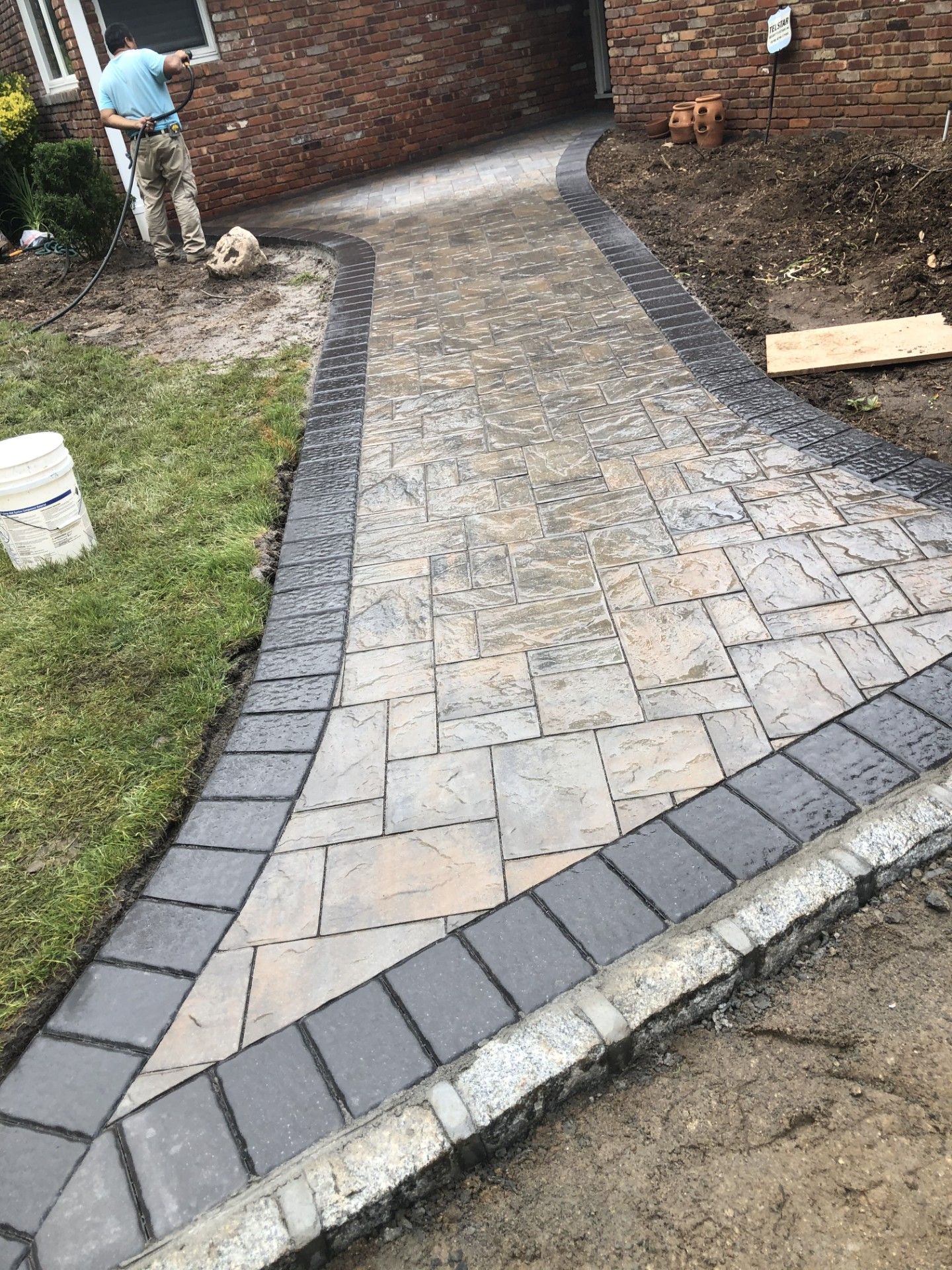A brick walkway is being built in front of a brick house.