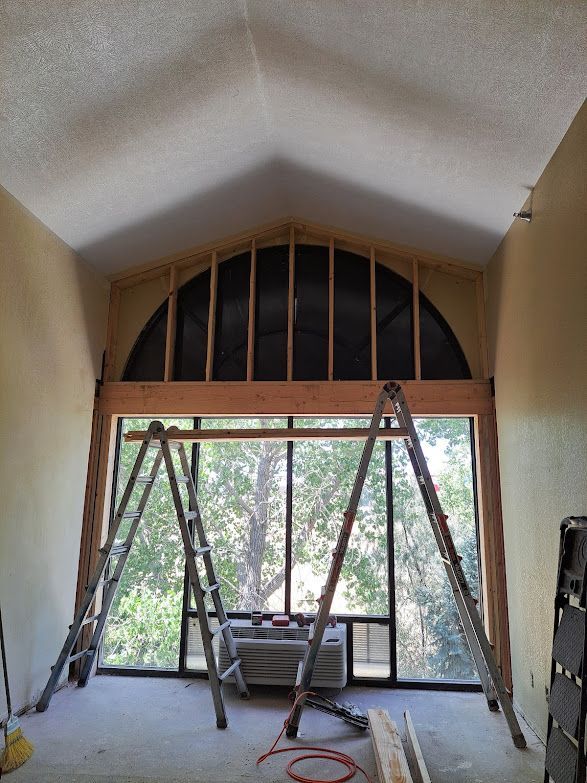 Interior view of a living room renovation featuring a vaulted ceiling, a wooden header, and an arched framed wall.