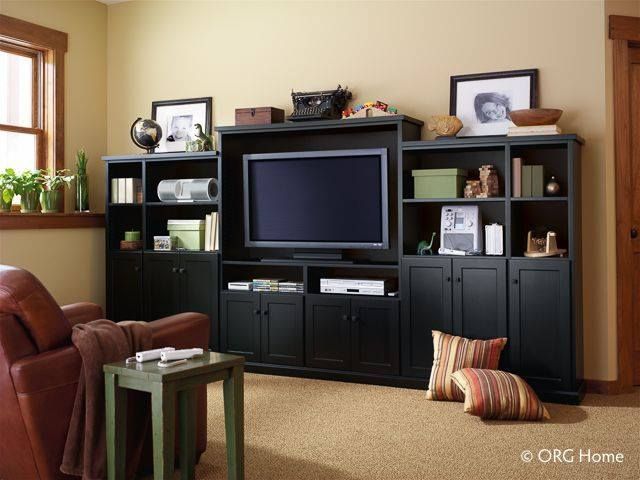 Black entertainment center with TV, shelves, and storage in a living room.