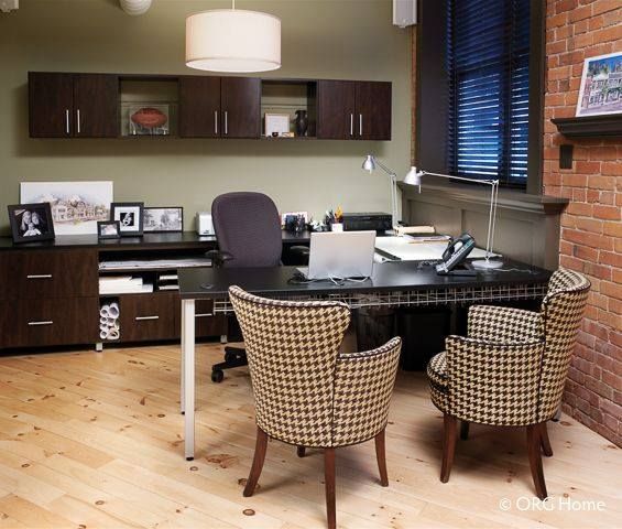 Office with desk, chairs, shelving, and a brick wall. Light brown wooden floor.