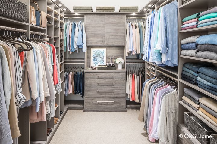 Walk-in closet with clothes on racks and shelves; gray wood cabinetry.