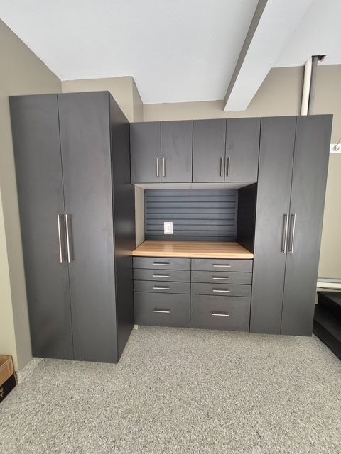 Dark gray garage storage cabinets and workbench against beige walls.