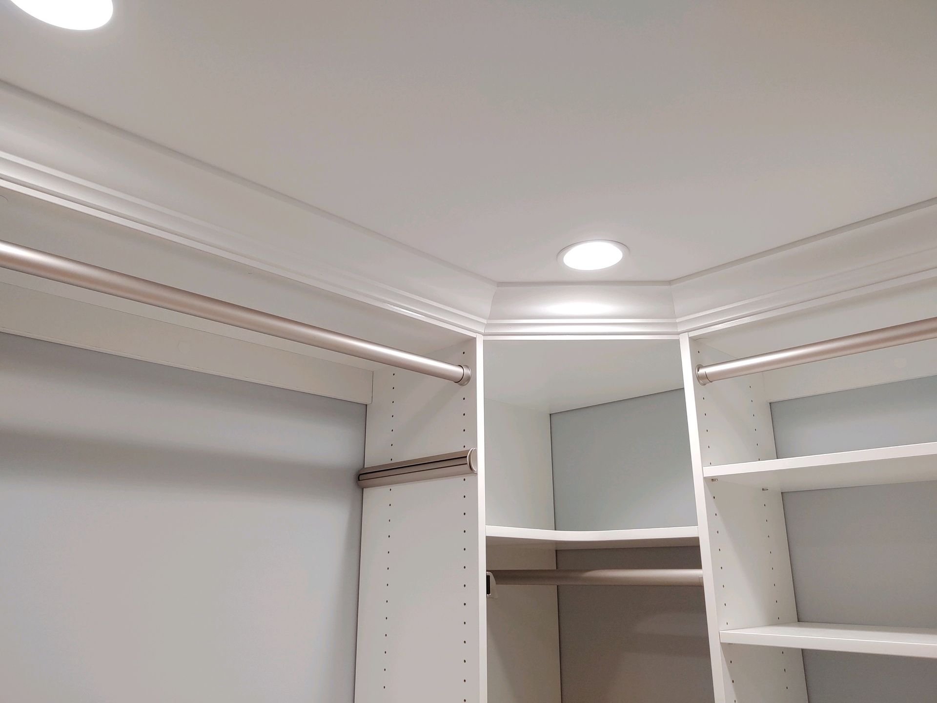 White closet interior with shelves, rods, and crown molding.