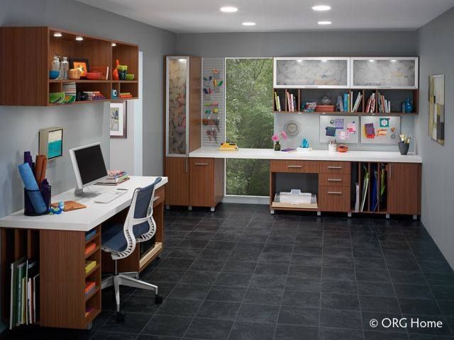 Home office with brown cabinets, white desk, and black tile floor. Window and workspace.