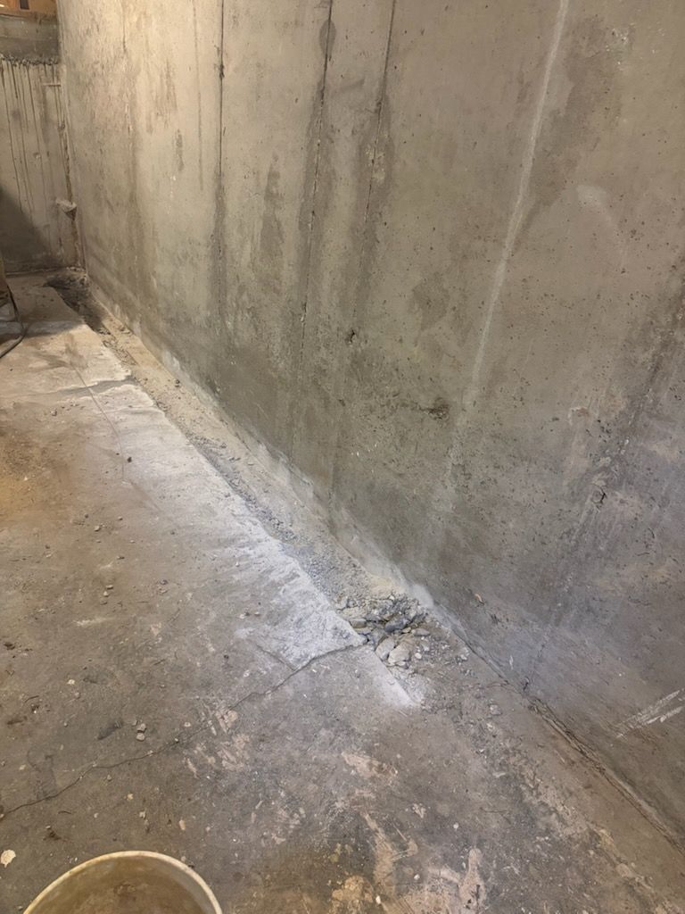 Concrete basement walls and floor with cracks and a seam.