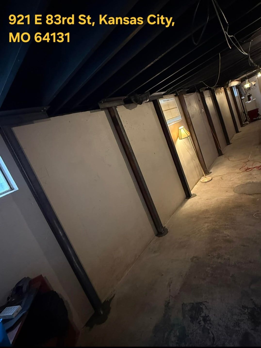 Basement with tan walls, dark support beams, and address 921 E 83rd St, Kansas City, MO 64131 at top.