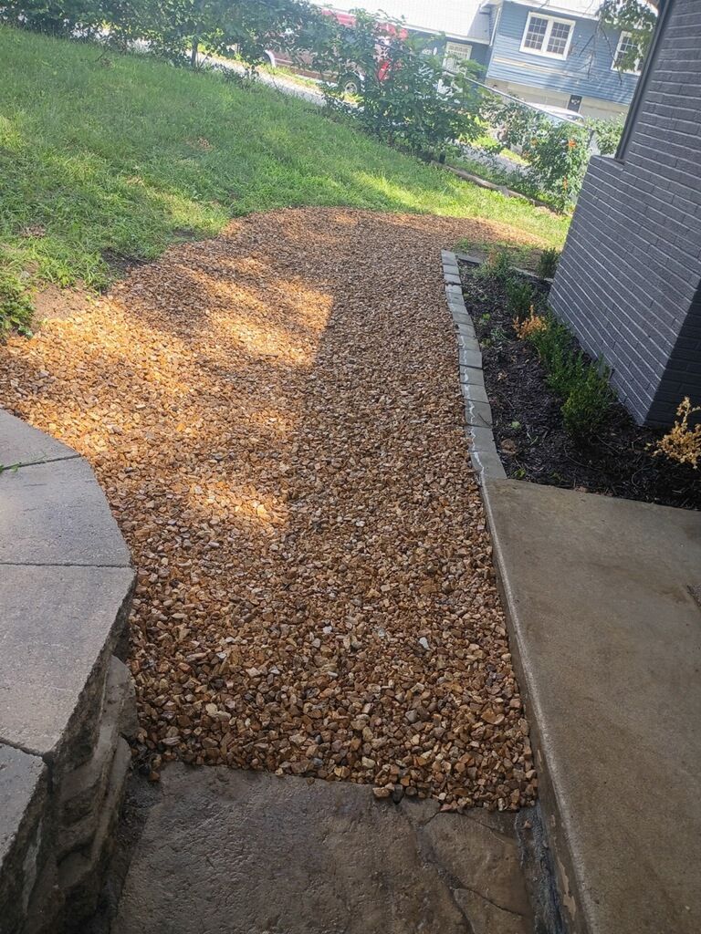 A gravel pathway leads from a concrete entrance up a slight slope to a grassy area.